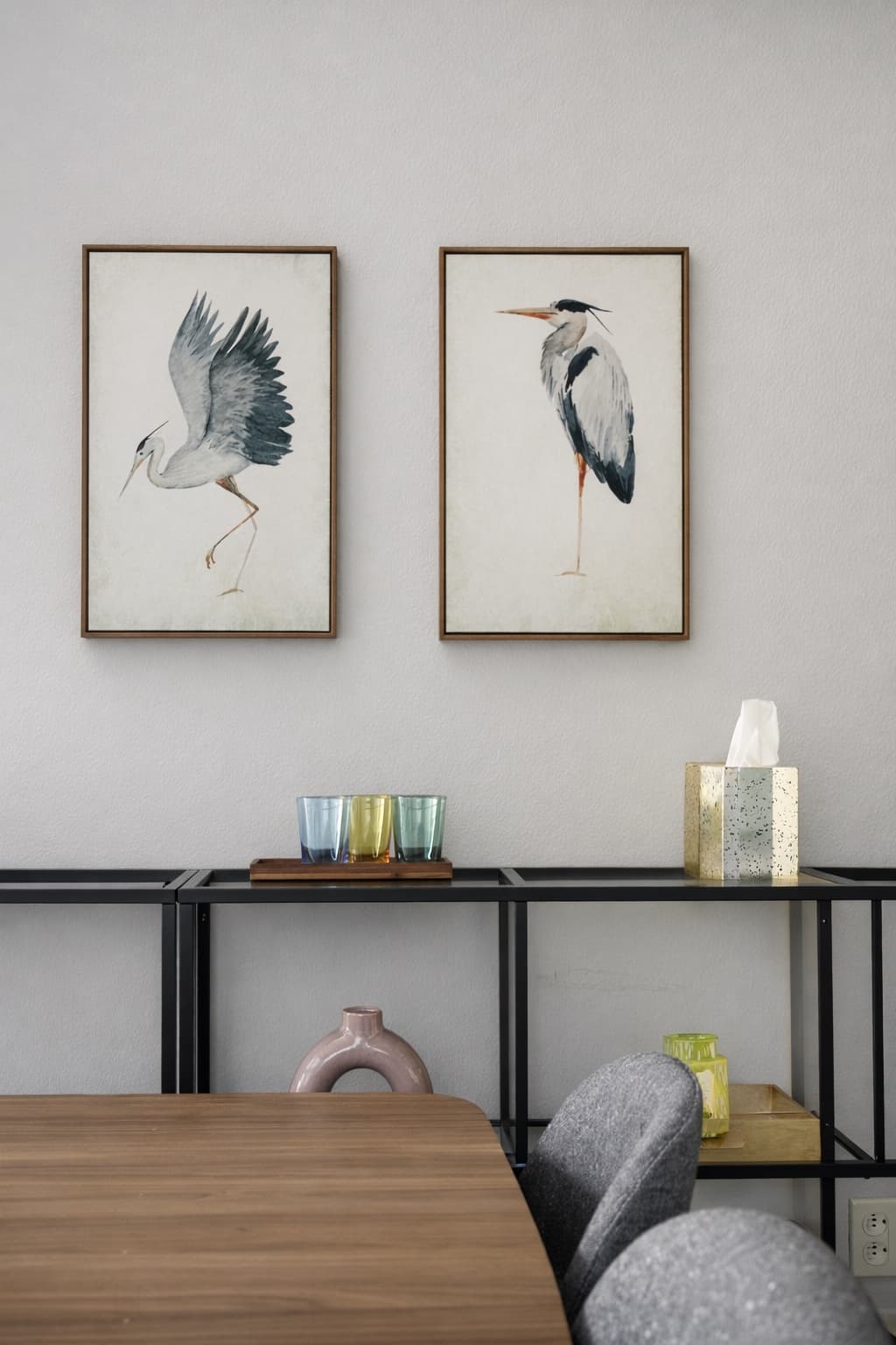 Pair of framed watercolor herons above a blackened-steel etagere styled with glassware
