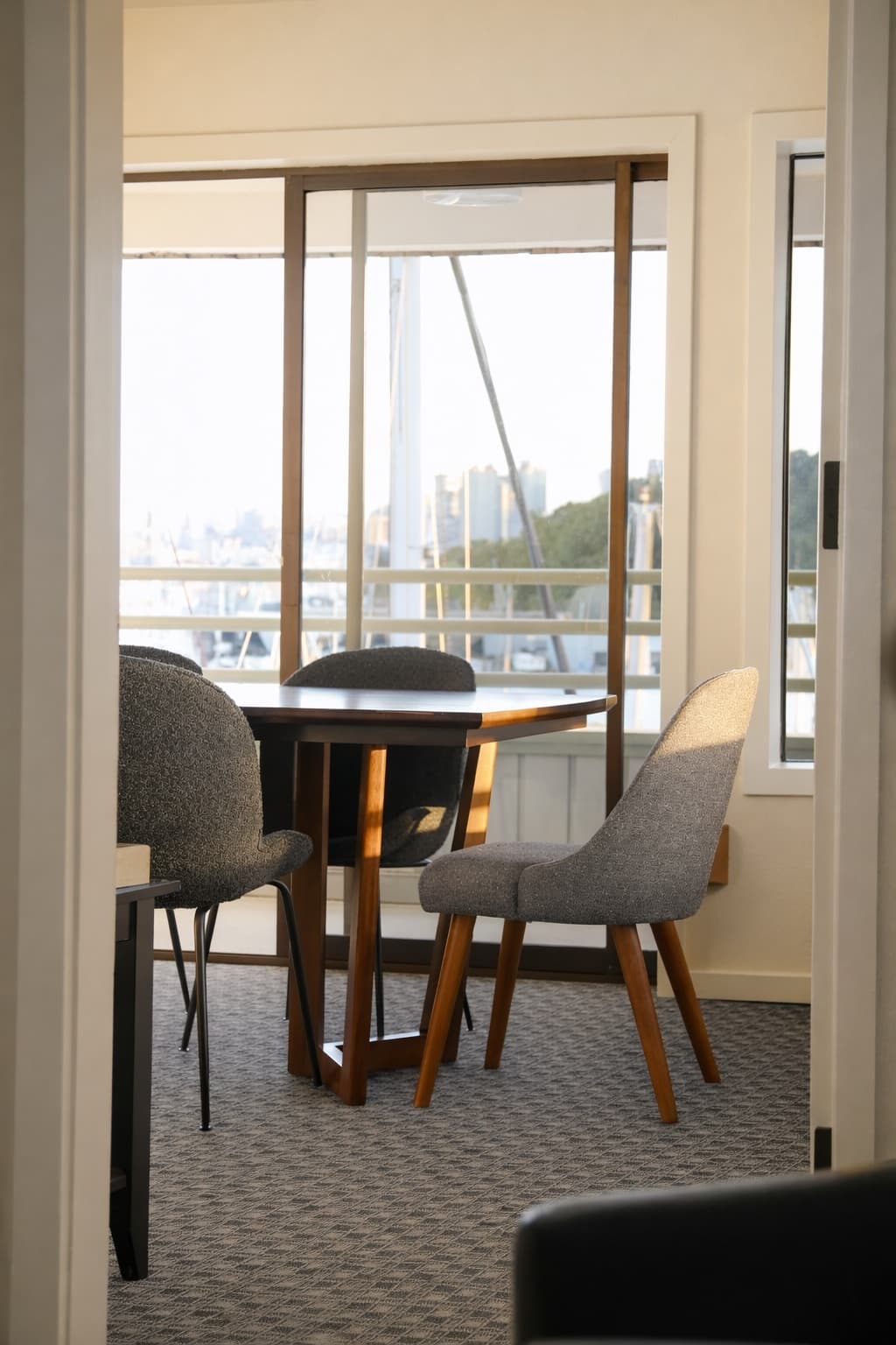 Conference table and boucle chairs in front of a marina-view window at golden hour